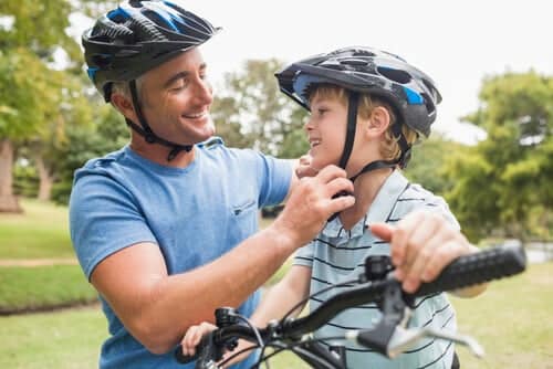 dad helping boy on bike with helmet