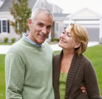 happy couple standing by white fence web