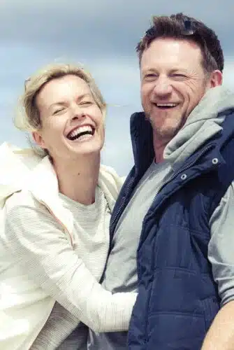 middle age couple laughing hugging on beach