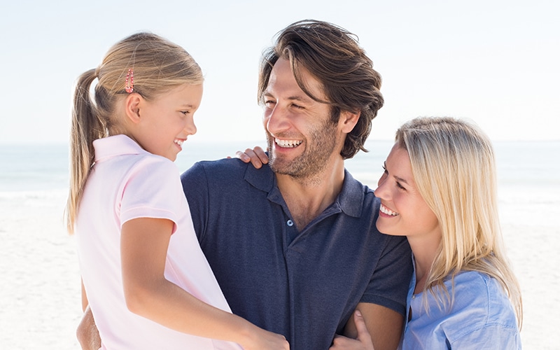 parents smiling daughter beach